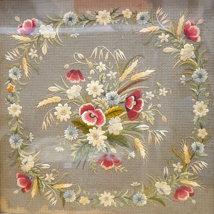 A late 19th century gilt framed silk and wool work embroidered fire screen, embroidered with a central sprig of poppies, wheat and wild flowers in a circular border of similar flowers, the frame with a decorative carved